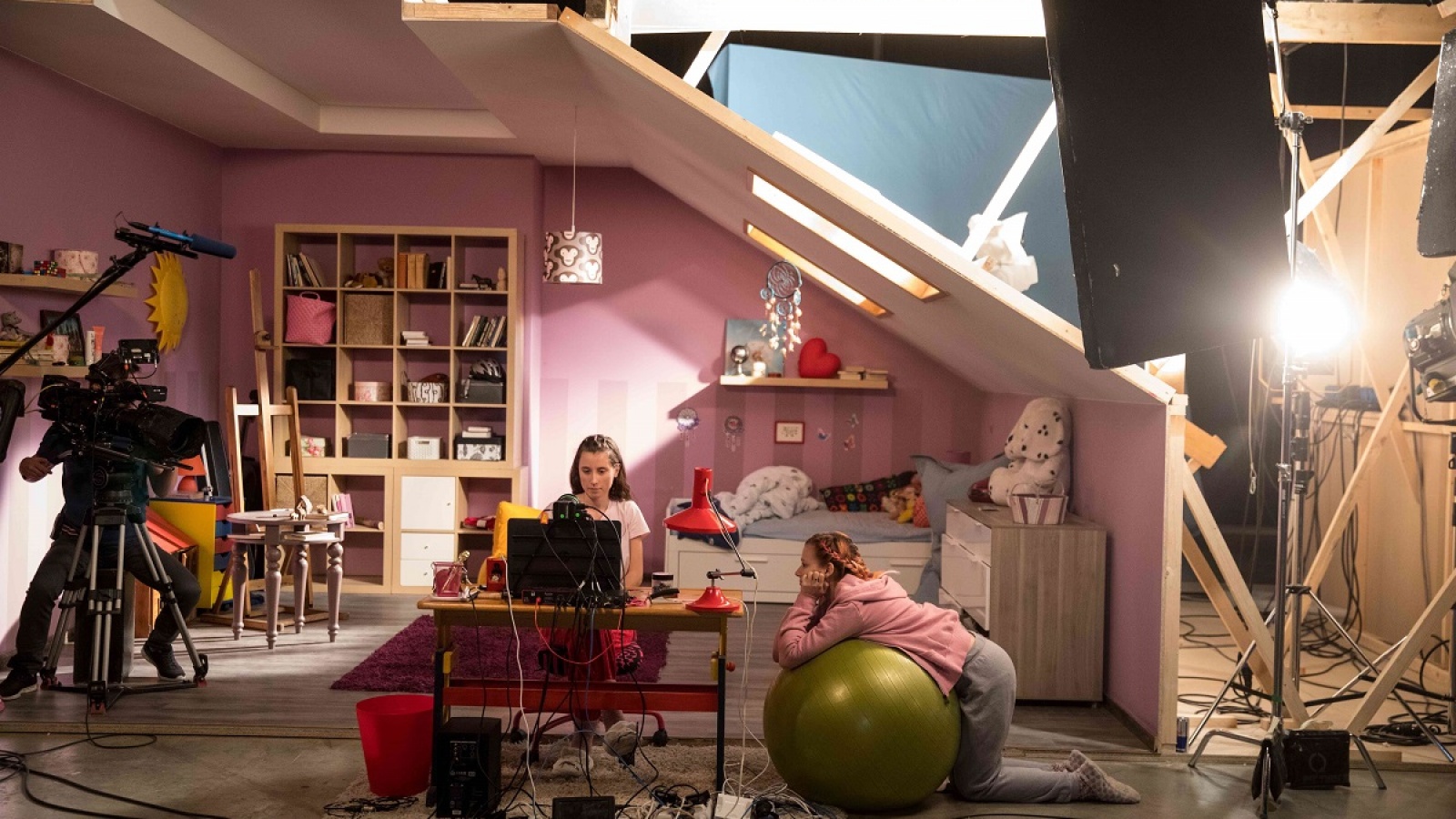 eng: The girls look at a monitor in a pavilion-like room.