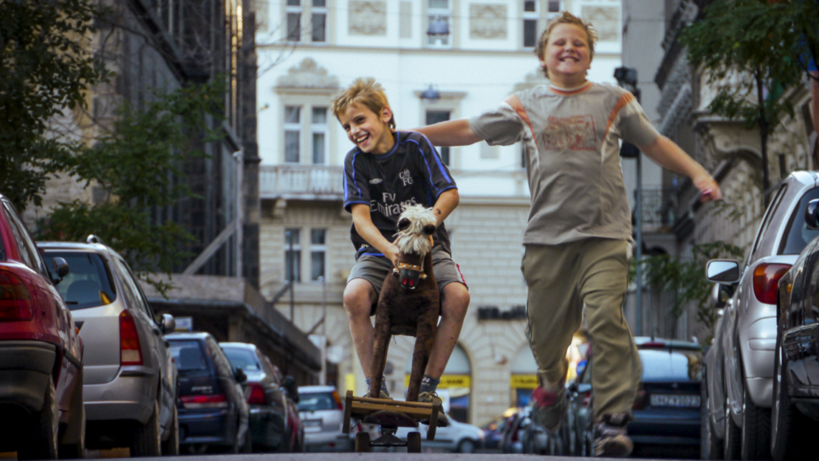 eng: Two smiling boys are running down the street.